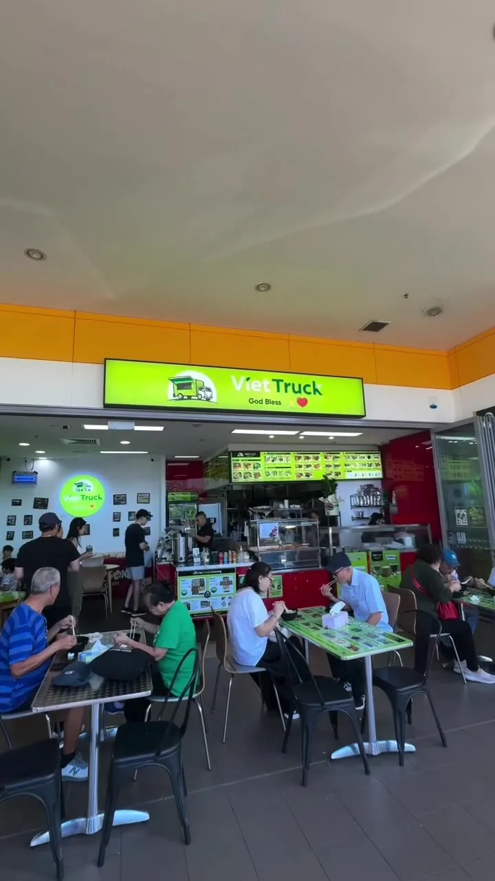 Inside the shop: the counter and menu boards, and a full room of people eating at the green tables